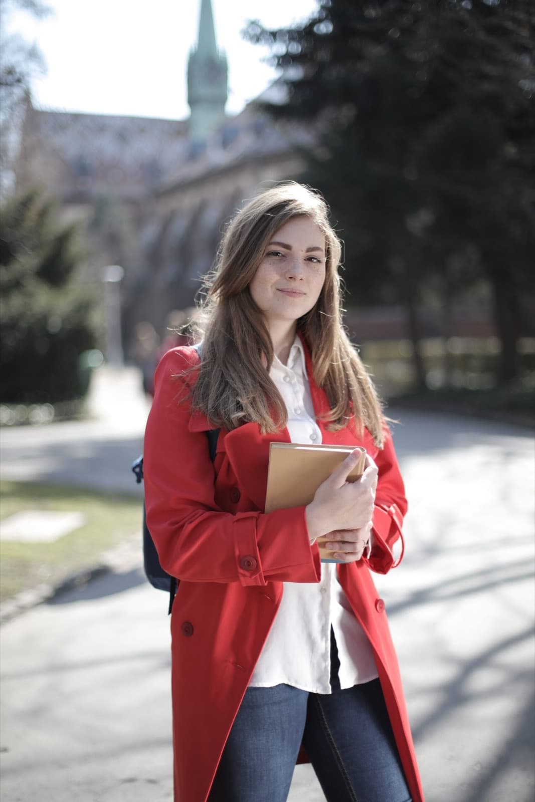 Étudiante avec un livre devant une université